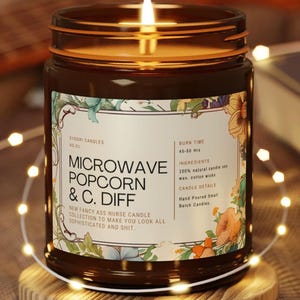 May include: A lit brown glass jar candle with a label that reads "MICROWAVE POPCORN & C. DIFF." The label has floral accents and the text "NEW FANCY ASS NURSE CANDLE COLLECTION TO MAKE YOU LOOK ALL SOPHISTICATED AND SHIT."
