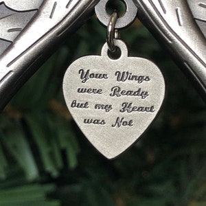 May include: A silver metal angel wing ornament with a heart-shaped charm that reads "Your Wings were Ready but my Heart was Not".