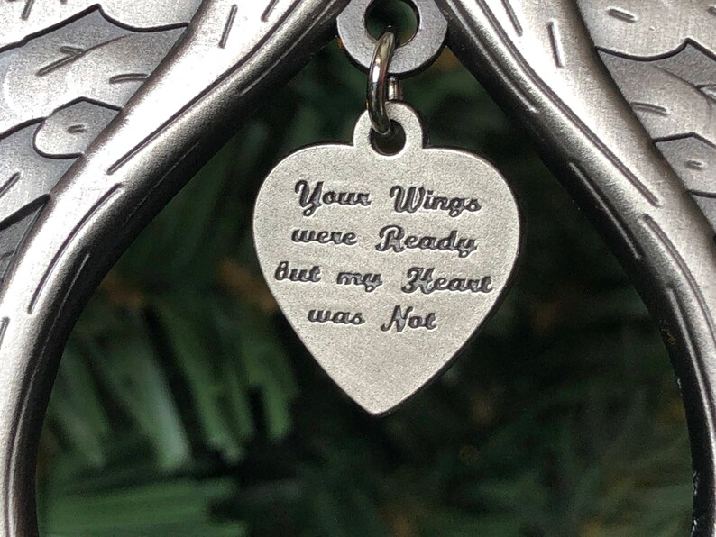 May include: A silver metal angel wing ornament with a heart-shaped charm that reads "Your Wings were Ready but my Heart was Not".