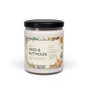 Op de afbeelding: Een witte kaars pot met een zwarte deksel en een label met een bloemenontwerp. Het label luidt "Weed & Buttholes" en bevat details over de kaars, zoals de brandtijd, ingrediënten en kaarsdetails.