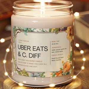 May include: A lit candle in a glass jar, with a label reading "UBER EATS & C. DIFF." The label also states "New Fancy Ass Nurse Candle Collection to Make You Look All Sophisticated and Shit." The candle sits on a wooden coaster and has a burn time of 45-50 hours.