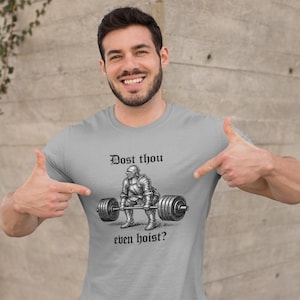 Pode incluir: Camiseta cinza claro com um gráfico de um cavaleiro levantando uma barra e o texto "Dost thou even hoist?". O cavaleiro está usando uma armadura. Gola redonda.