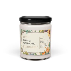 May include: A glass candle jar with a black lid. The label reads "Queefer Sutherland" and features a floral design. The candle is hand-poured and made in the UK. It has a burn time of 50-60 hours.