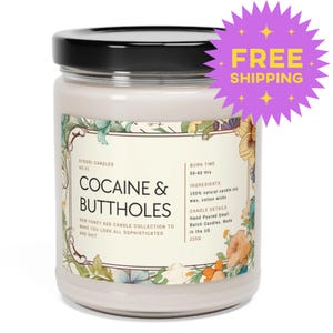 May include: A white jar candle with a black lid, featuring a label with the text "COCAINE & BUTTHOLES." The label includes floral and botanical illustrations. The candle is part of the "NEW FANCY ASS CANDLE COLLECTION."