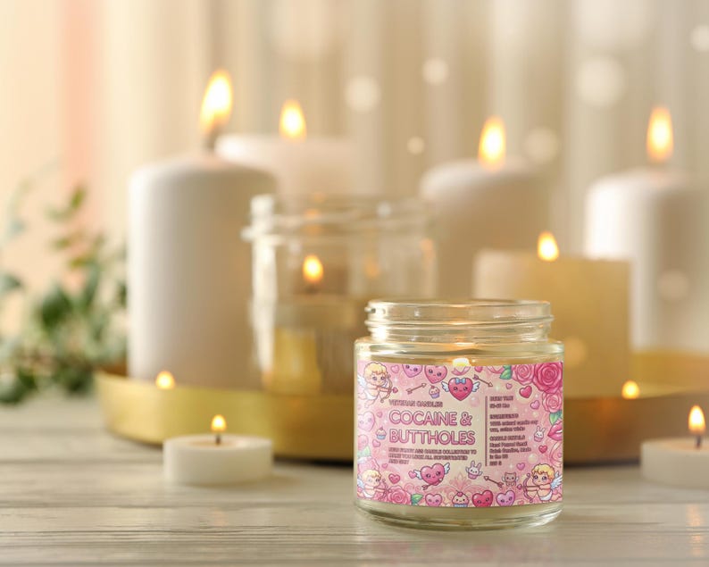 May include: A lit jar candle with the text "COCAINE & BUTTHOLES" on a pink label, surrounded by cartoon hearts, cherubs, and roses. Several other lit candles of varying sizes are in the background, creating a warm, inviting ambiance.