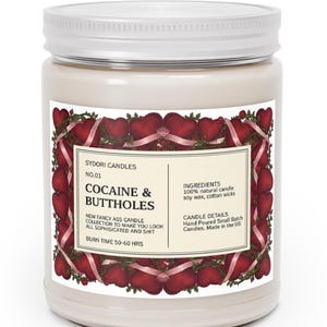 Puede incluir: Una vela en tarro blanco con tapa blanca. La etiqueta dice "COCAINE & BUTTHOLES" con un dise&ntilde;o de coraz&oacute;n y cinta. La etiqueta tambi&eacute;n indica que la vela est&aacute; hecha con cera de soja y mechas de algod&oacute;n, y tiene un tiempo de combusti&oacute;n de 50-60 horas.