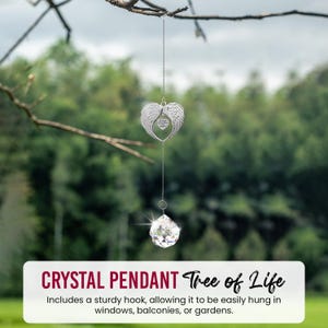 May include: A silver-colored crystal pendant with a heart-shaped design and angel wings. The pendant hangs from a chain and features a large, faceted crystal at the bottom. Text on the image reads "CRYSTAL PENDANT Tree of Life".