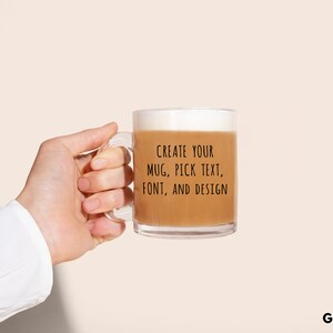 Peut inclure: Un mug en verre transparent rempli d'une boisson brun clair, tenu par une personne. Le mug a une anse et le texte "CREATE YOUR MUG, PICK TEXT, FONT, AND DESIGN." Les mots "GLASS MUG" sont en bas.