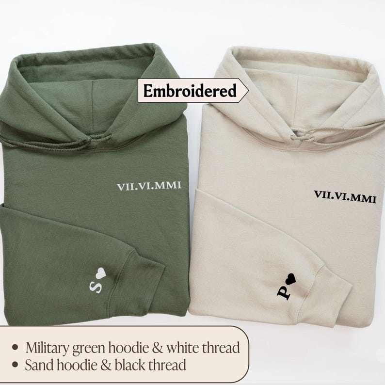 May include: Two embroidered hoodies, one in military green with white thread and the other in sand with black thread. Both hoodies feature the text "VII.VI.MMI" and a small heart on the sleeve.