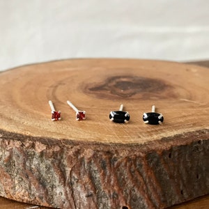 May include: Four pairs of earrings on a wooden surface. Two pairs are red and two pairs are black.