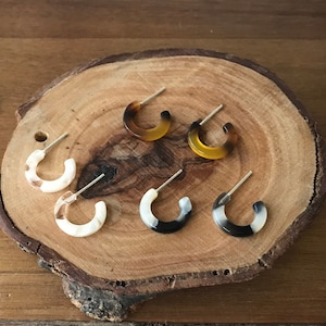 May include: Six pairs of hoop earrings in various patterns. Two pairs are white with black accents, two pairs are brown with black accents, and two pairs are brown with yellow accents.