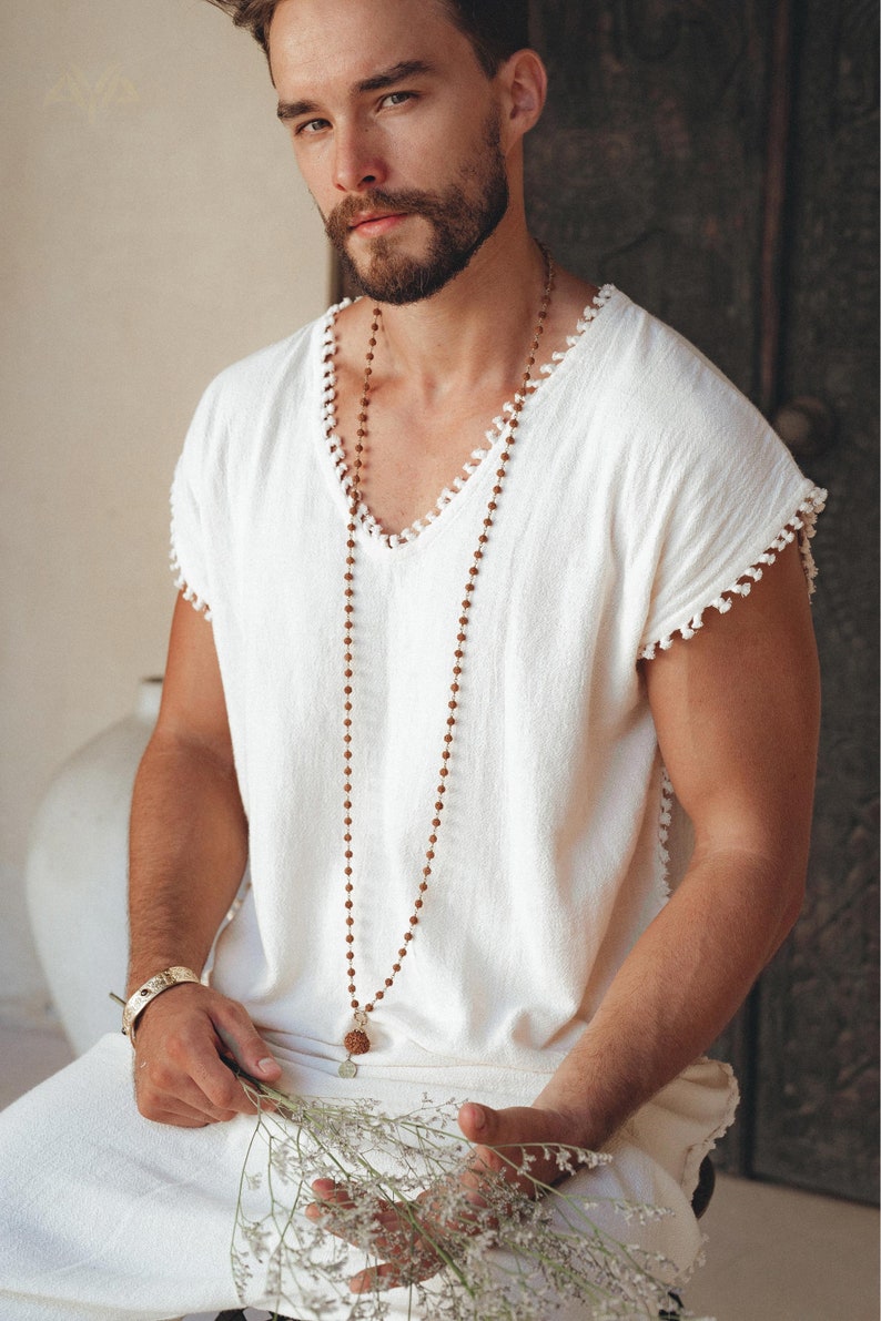 Get the perfect off-white T-shirt with a casual Boho vibe. With the handmade details and knotwork, this is the ideal choice for men's fashion. Make sure to check out the sizes before shopping.