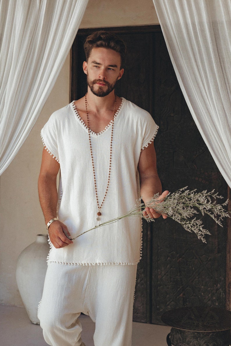 Add a splash of Boho charm to your wardrobe with this handmade off-white T-shirt featuring intricate knots and adorned with handmade details. Be sure to check out the size range and find the perfect fit.