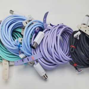 Może przedstawiać: Cztery zwinięte kable z różnokolorowymi osłonami: jasnoniebieski, lawendowy, turkusowy i czarny. Każdy kabel ma biały złącze na jednym końcu i złącze wielopinowe na drugim końcu.