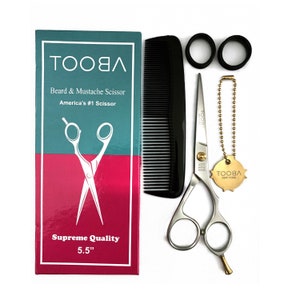 May include: A silver beard and mustache scissor with a gold handle, a black comb, two black hair ties, and a gold chain with a gold tag that says "TOOBLA NEW YORK". The scissor is 5.5 inches long. The packaging is blue and pink and says "TOOBLA Beard & Mustache Scissor America's #1 Scissor Supreme Quality 5.5""