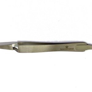 May include: A stainless steel surgical tweezer with a curved tip and the text "boromed". The tweezer is designed for precision and is likely used in medical or laboratory settings. The metal has a brushed finish.