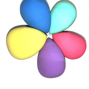 May include: Five teardrop-shaped makeup sponges in different colors: blue, turquoise, yellow, purple, and pink.