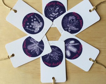 May include: Six white gift tags with blue circles and white floral illustrations. The text "Merry Xmas" is written in pink on each tag.