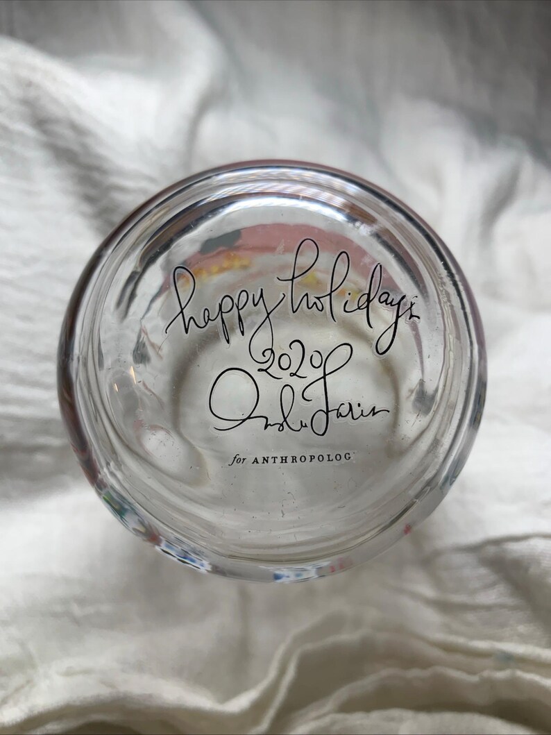 Puede incluir: Vaso de vidrio transparente con las palabras "happy holidays 2020" y la firma "Ondine Jarin" en escritura negra. Tambi&eacute;n son visibles las palabras "for ANTHROPOLOG".