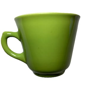 May include: A bright green ceramic coffee mug with a curved handle. The mug has a slightly flared shape and a glossy finish. The green colour is consistent throughout the mug.