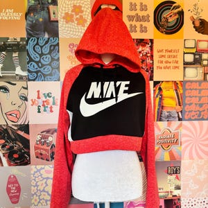May include: Red and black Nike cropped hoodie with the Nike logo in white. The hoodie has a hood and long sleeves. The background is a collage of various images and text.