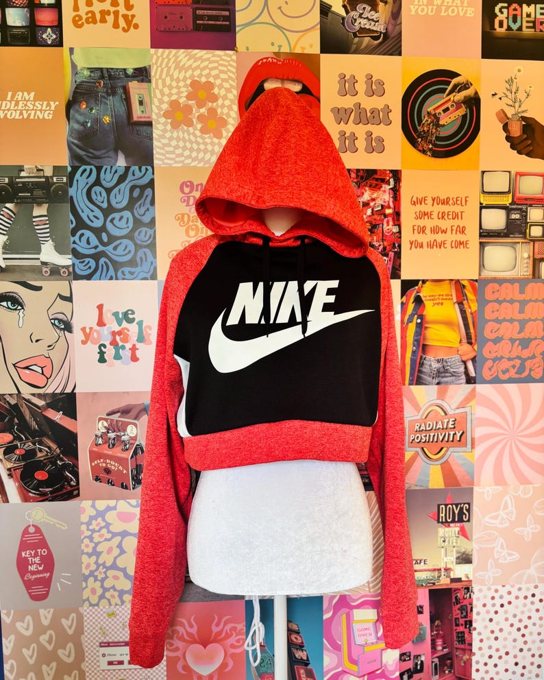 May include: Red and black Nike cropped hoodie with the Nike logo in white. The hoodie has a hood and long sleeves. The background is a collage of various images and text.