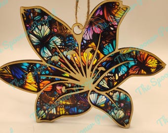 May include: Wooden ornament shaped like a lily flower with a colorful butterfly pattern. The ornament has a string for hanging.