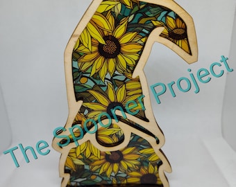 May include: Wooden gnome ornament with a sunflower pattern. The gnome is shaped like a traditional gnome with a tall hat and a beard. The ornament is perfect for adding a touch of whimsy to your home decor.