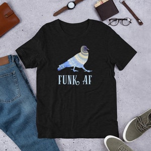 May include: Black t-shirt featuring a decorative pigeon design in blue and yellow with the text "FUNK AF" in light blue. The pigeon design has intricate patterns. The shirt is made of a soft material.