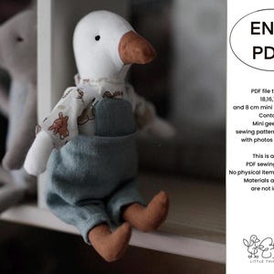 Op de afbeelding: Een digitaal PDF-naaipatroon voor een mini-gans knuffel, met tekst die maten van 18, 16, 13, 10 en 8 cm aangeeft. De afbeelding toont een witte stoffen ganzenpop met een bruine snavel, gekleed in een shirt met patroon en een blauwe tuinbroek.