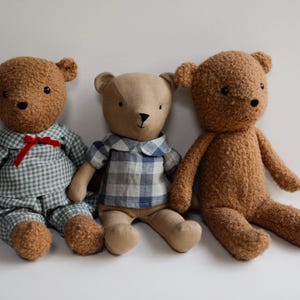 May include: Three plush teddy bears, one wearing a blue and white plaid shirt, one wearing a blue and white gingham shirt, and one wearing a brown fuzzy coat.