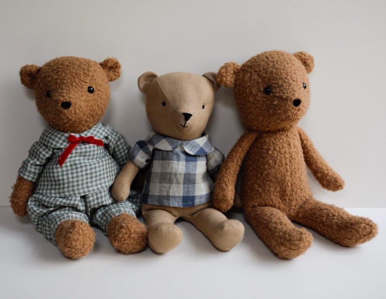 May include: Three plush teddy bears, one wearing a blue and white plaid shirt, one wearing a blue and white gingham shirt, and one wearing a brown fuzzy coat.