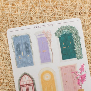 Pode incluir: Uma folha de adesivos com v&aacute;rias portas ilustradas com cores e designs diferentes. As portas s&atilde;o decoradas com trepadeiras, flores e outros detalhes. A folha &eacute; etiquetada com "FRAI. oh SHOP".