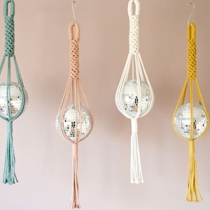 Pode incluir: Quatro macramês suspensos com bolas de discoteca dentro. Os macramês são feitos com corda de algodão natural e estão disponíveis em quatro cores: verde, bege, branco e amarelo.
