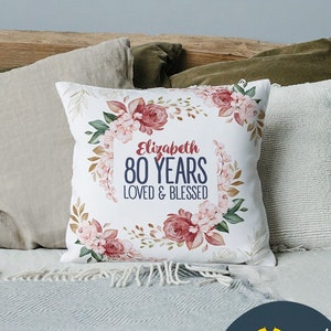 May include: White pillow with a floral design and the text "Elizabeth 80 YEARS LOVED & BLESSED".