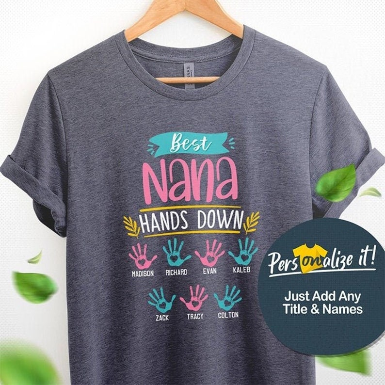 May include: Gray t-shirt with the text "Best Nana Hands Down" in colorful lettering.  The shirt features a design of colorful handprints with names below each handprint: Madison, Richard, Evan, Kaleb, Zack, Tracy, Colton.  The text "Personalize it! Just Add Any Title & Names" is also included.