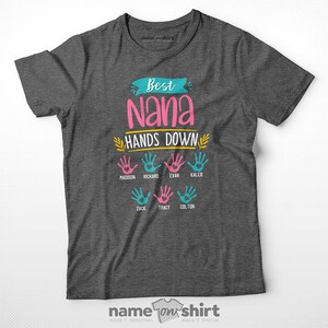May include: A gray t-shirt with the text "Best Nana Hands Down" in pink, yellow, and blue. There are seven handprints with names below each handprint: Madison, Richard, Evan, Kaleb, Zack, Tracy, and Colton.