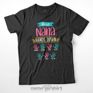May include: Black t-shirt with the text "Best Nana Hands Down" in pink and yellow.  There are six handprints in pink and blue with names written below each handprint: Madison, Richard, Evan, Caleb, Zack, Tracy, and Colton.