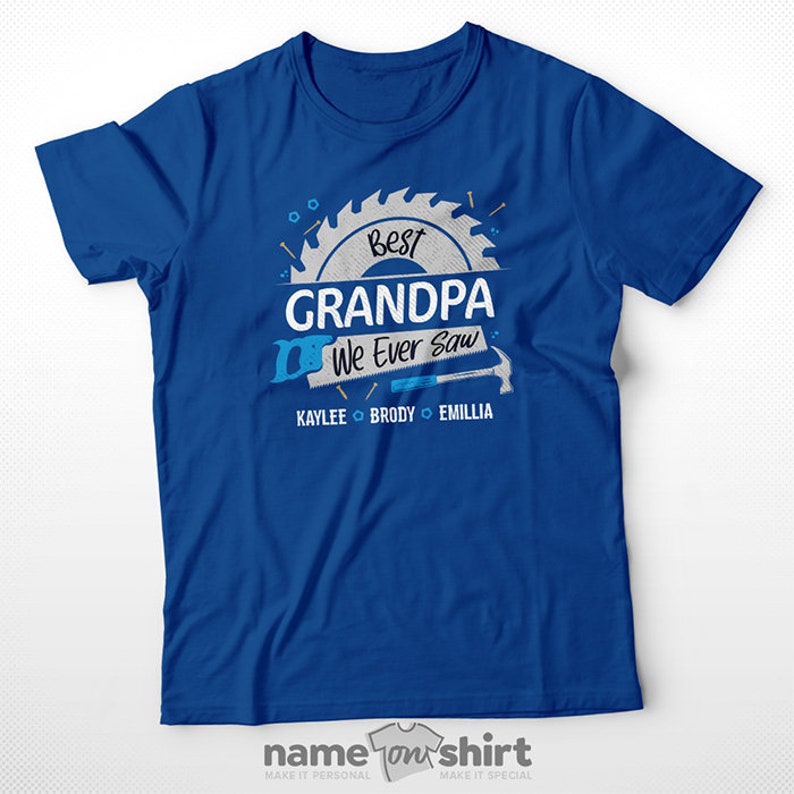 Pu&ograve; includere: Maglietta blu con una grafica di lama da sega bianca che dice "Best Grandpa We Ever Saw" con i nomi Kaylee, Brody ed Emillia sotto.
