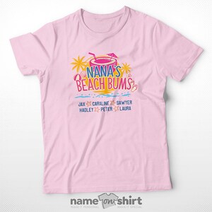 May include: Pink t-shirt with a graphic of a tropical drink and the text "Nana's Beach Bums". Below the graphic are the names "Jax, Caraline, Sawyer, Hadley, Peter, Laura".