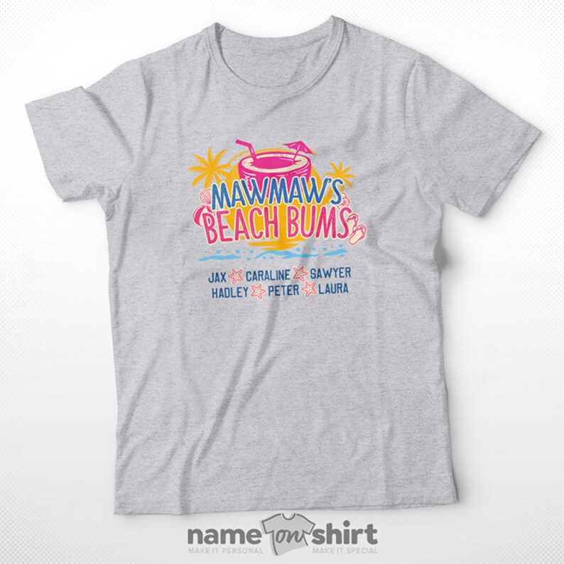 May include: Gray t-shirt with a graphic of a pink and yellow beach scene with the text "Mawmaw's Beach Bums". The graphic also includes a pink and yellow cocktail with a straw and a blue umbrella. Below the graphic are the names "Jax, Caraline, Sawyer, Hadley, Peter, Laura" in black text.