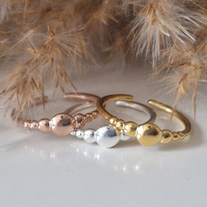 Könnte beinhalten: Drei zarte Ringe mit einem Perlenmuster. Die Ringe sind aus Silber, Gold und Roségold.