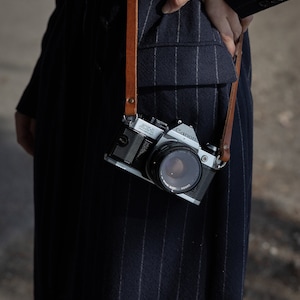 Tracolla in pelle per fotocamera. Compatibile con fotocamere Leica, canon, Nikon, fuji Sony e tutte le fotocamere vintage a pellicola. Fatta a mano in Italiana. Vera pelle conciata al vegetale italiana.