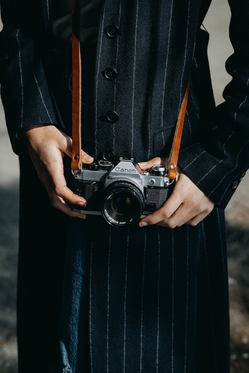 Tracolla in pelle per fotocamera. Compatibile con fotocamere Leica, canon, Nikon, fuji Sony e tutte le fotocamere vintage a pellicola. Fatta a mano in Italiana. Vera pelle conciata al vegetale italiana.