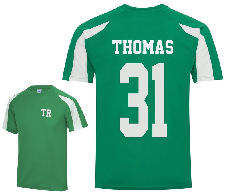 May include: Two green athletic shirts with white accents. One shirt has the initials "TR" on the front. The other shirt has the name "THOMAS" and the number "31" on the back. Both shirts have white shoulder panels.
