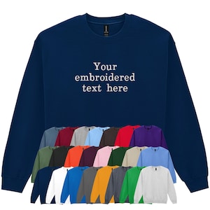 May include: A navy blue sweatshirt with the text "Your embroidered text here" in white. Below are examples of other available colours, including red, green, and grey. This customizable sweatshirt is perfect for personalised gifts or team apparel.