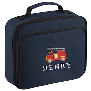 May include: Navy blue lunch bag with a black zipper and handle. The bag features an embroidered red fire truck with a ladder and the name "HENRY" in white lettering. The bag is rectangular and has a front pocket.