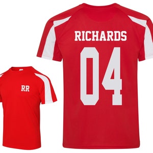 May include: Two red athletic shirts with white accents. One shirt displays "RR" in white, while the other features "RICHARDS" and the number "04" in white. Both shirts have a sporty design.
