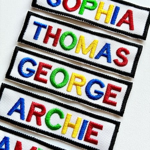 May include: Embroidered name patches with white fabric, black borders, and colorful lettering. Names include Sophia, Thomas, George, Archie, and more. Each patch features a different color for each letter, creating a rainbow effect.