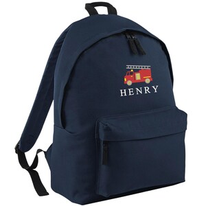 May include: Navy blue backpack with a red and yellow embroidered fire truck design. The backpack has a front pocket, black zippers, and the name "HENRY" embroidered in white. The backpack has black shoulder straps and a top handle.